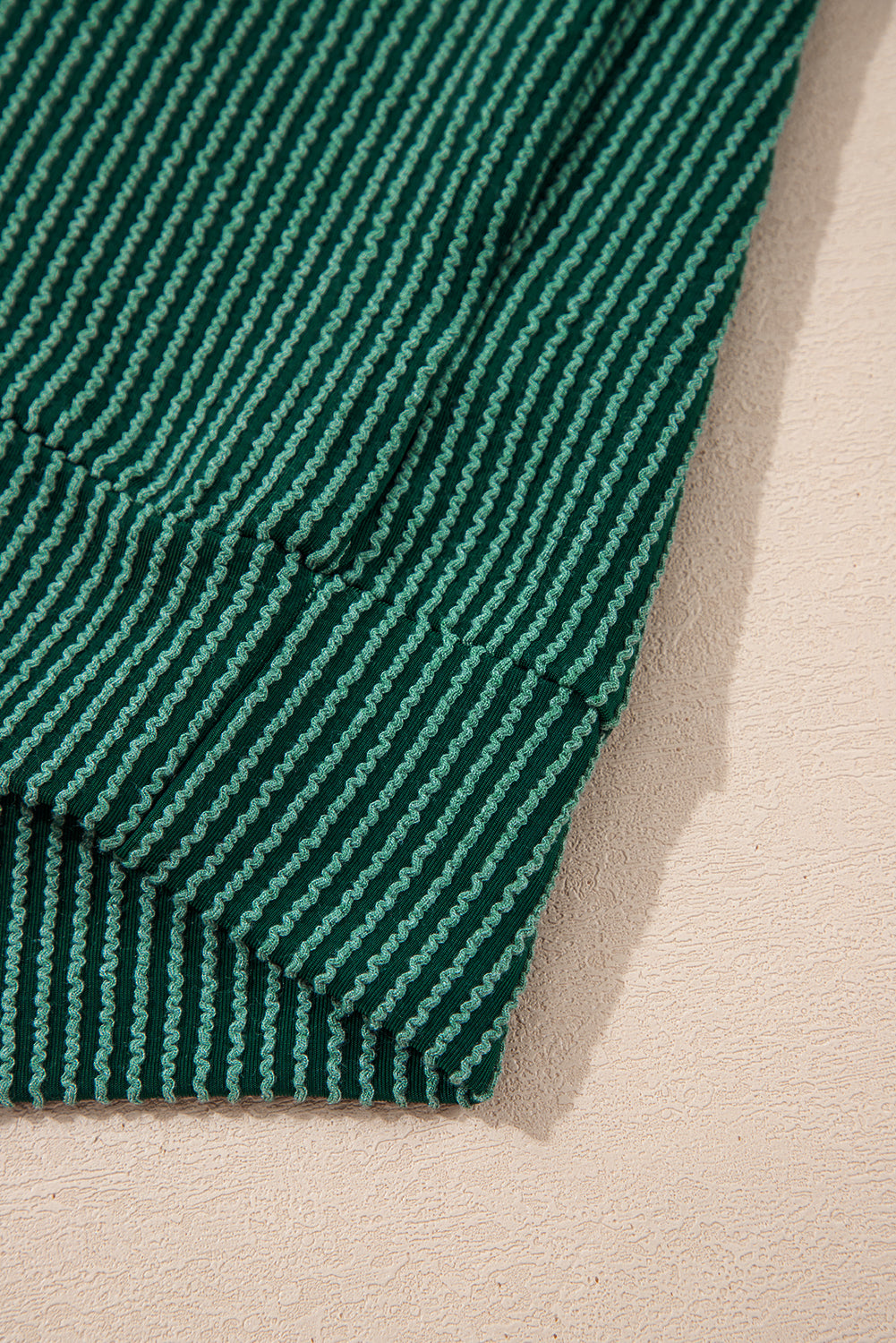 Hem detail of green Evergreen JOLLY Corded Top with ribbed knit. Soft and stretchy fabric from Faith & Co. Boutique.