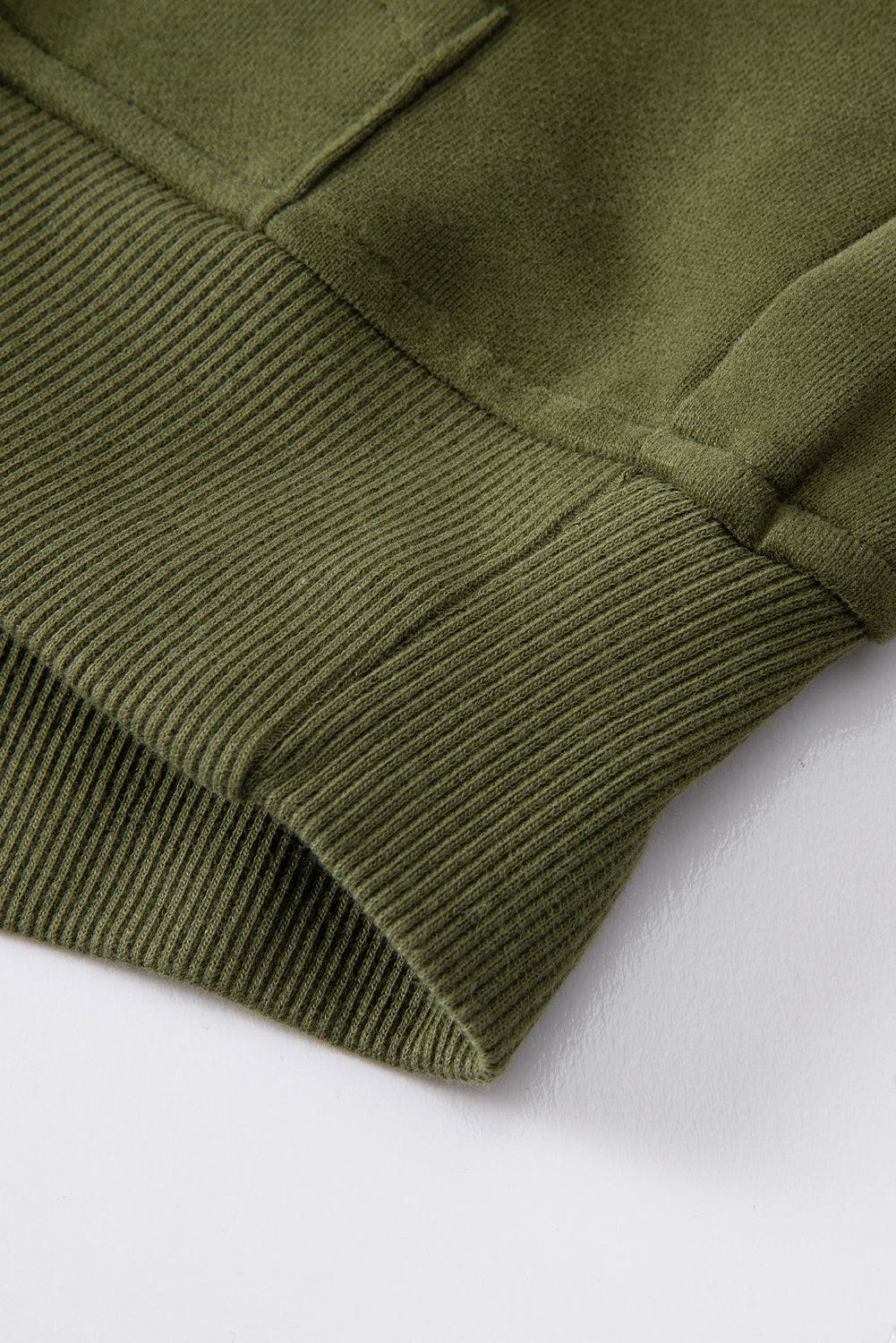 a close up of a green sweater on a white surface