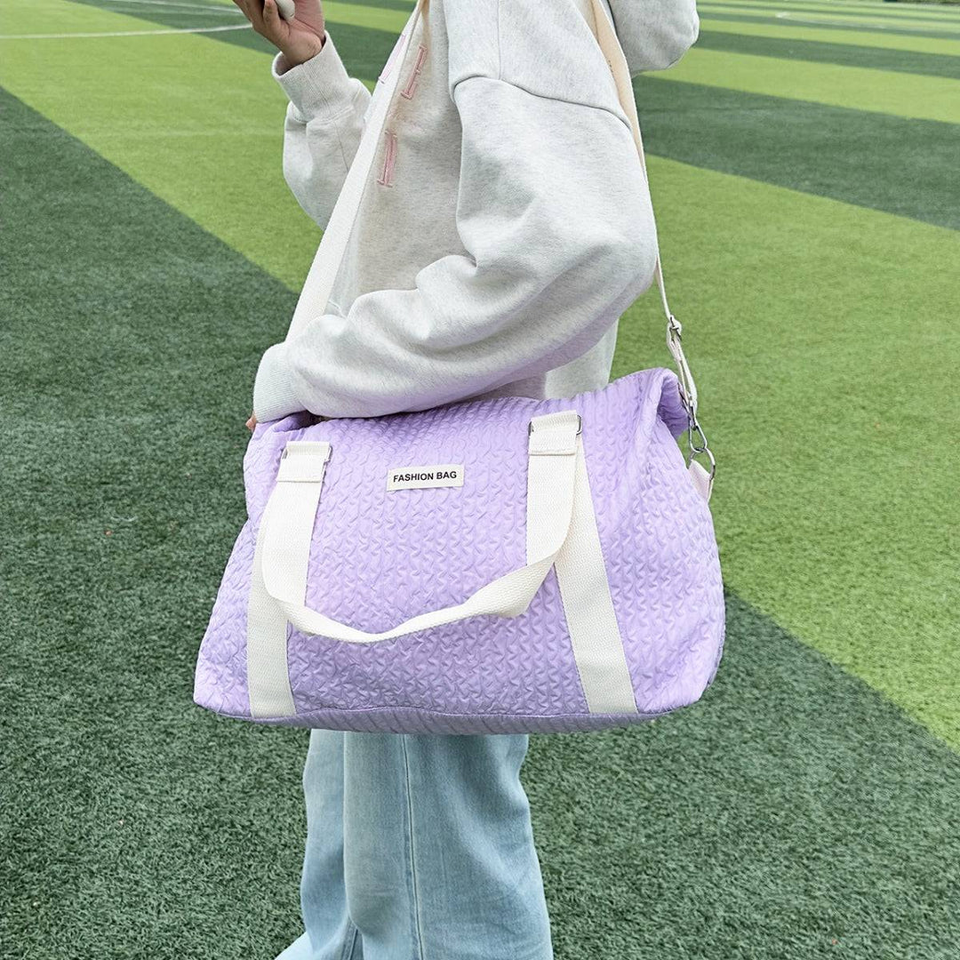 a woman standing on a field holding a purple bag