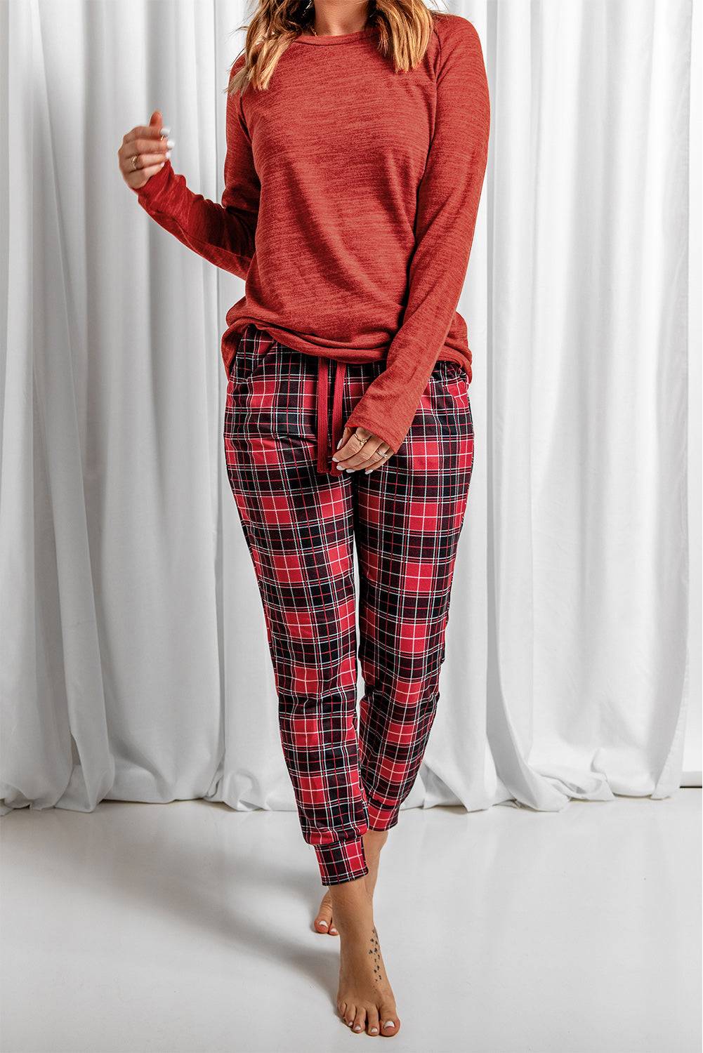 a woman wearing a red sweater and plaid pants