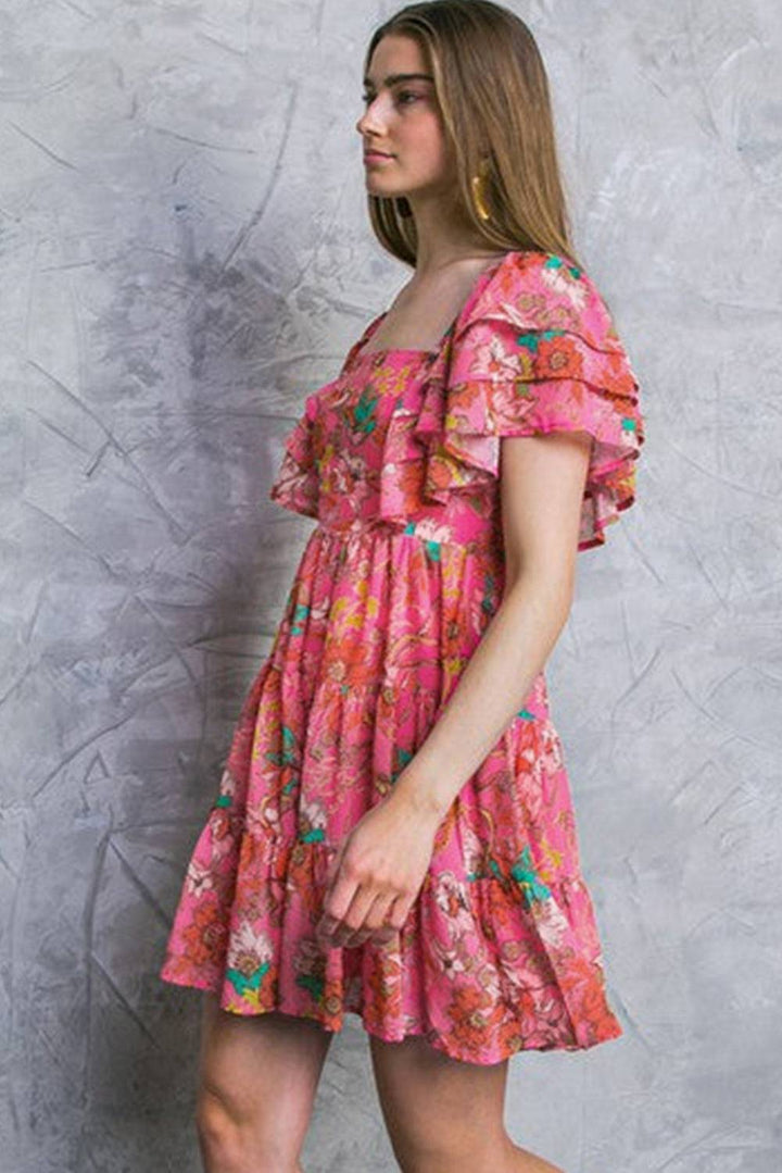 a woman in a pink dress is standing against a wall