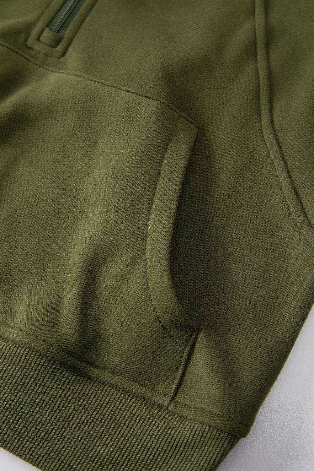 a close up of a green hoodie on a white surface