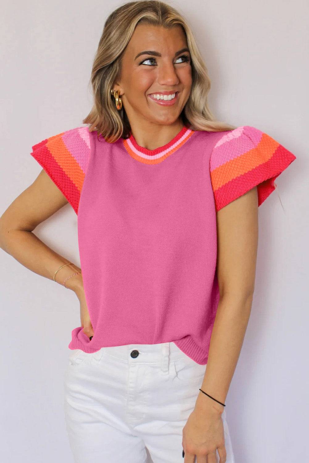 a woman wearing a pink sweater and white pants