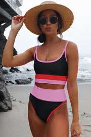 a woman in a pink and black one piece swimsuit on the beach