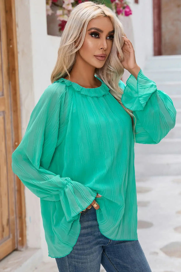 a woman wearing a green blouse and jeans