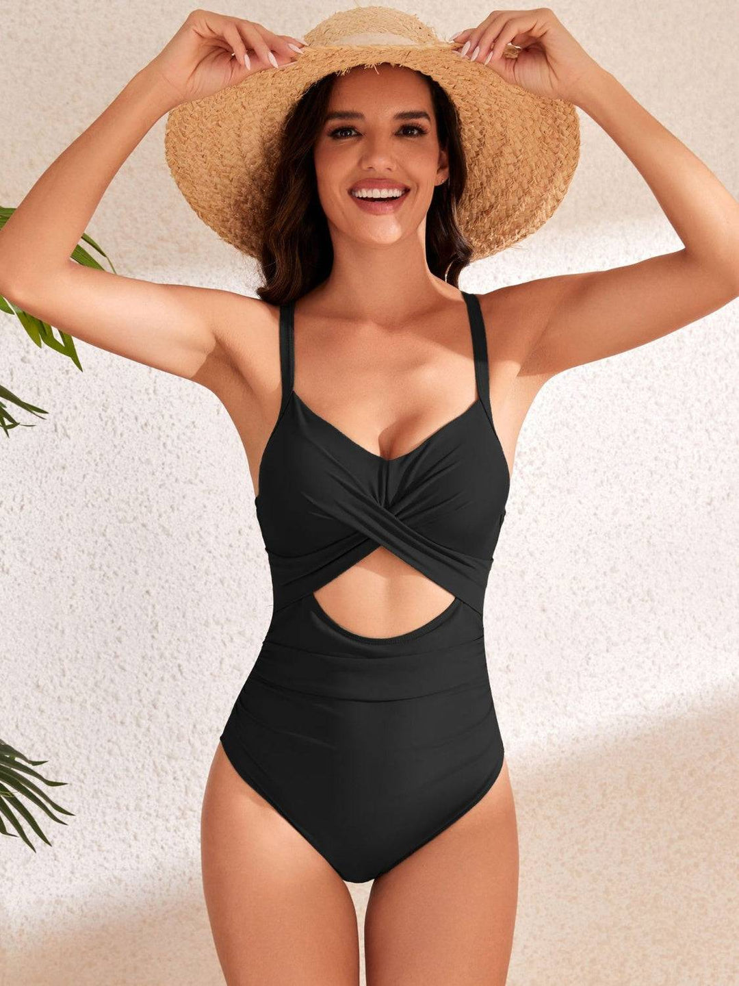 a woman wearing a black one piece swimsuit and a straw hat