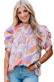 a woman with blonde hair wearing a colorful top