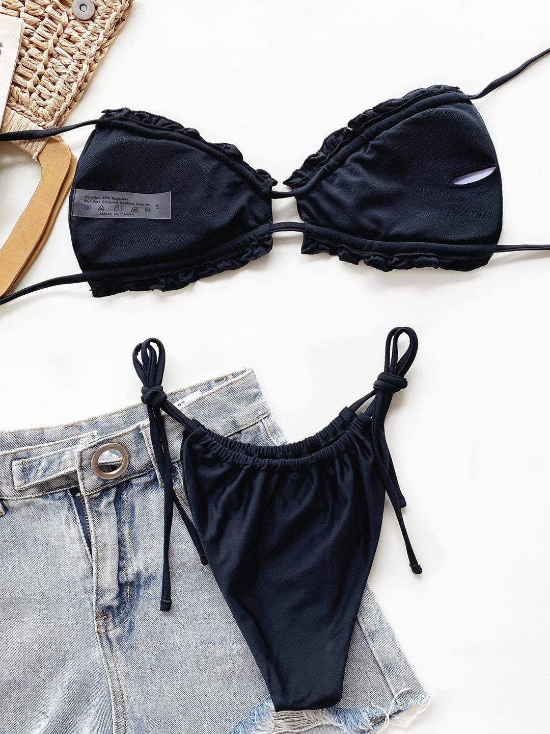 a pair of black bikini tops next to a pair of denim shorts