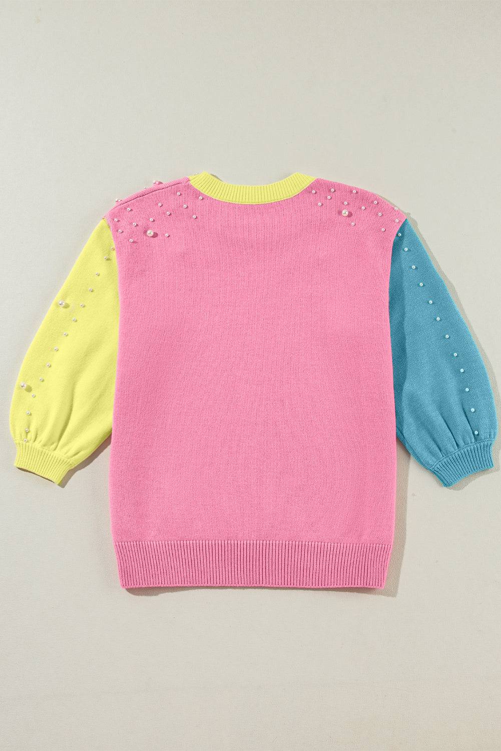 a pink, yellow and blue sweater on a white background