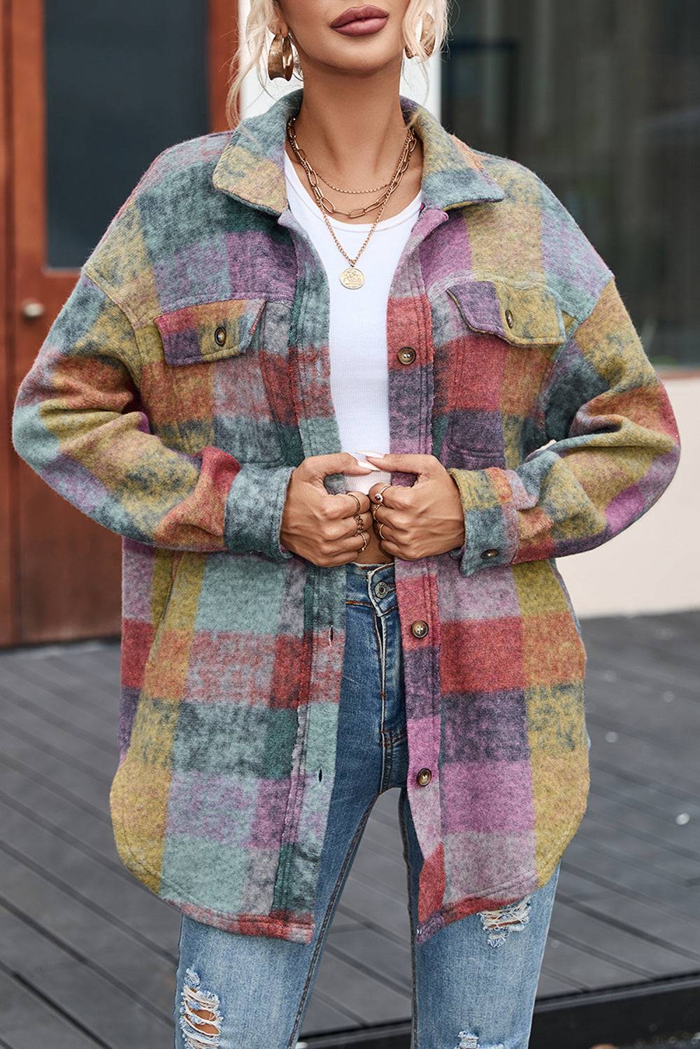 a woman wearing a multicolored jacket and ripped jeans