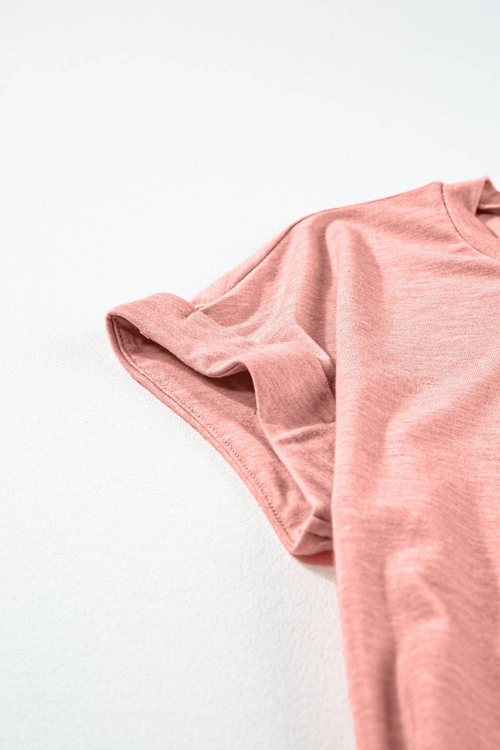 a pink shirt laying on a white surface