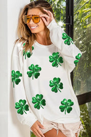 a woman wearing a white sweater with green shamrocks on it