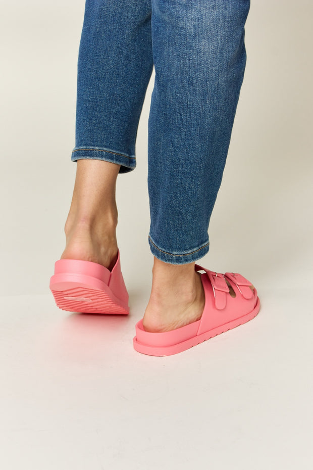 a woman's feet in pink shoes and jeans