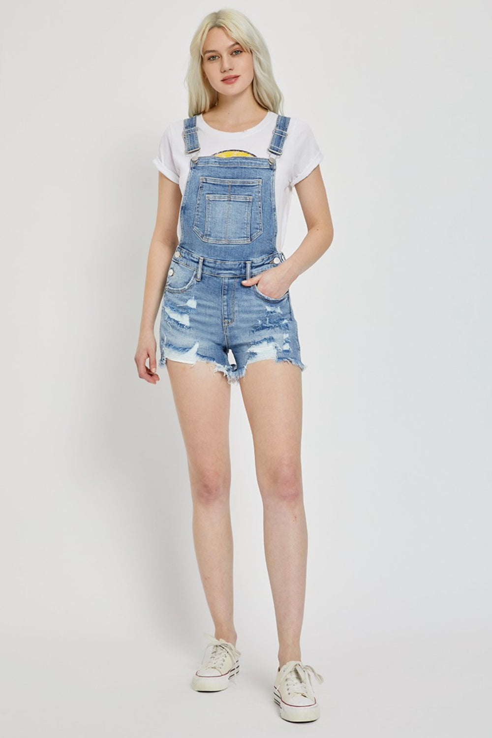 a woman in a white t - shirt and denim overalls