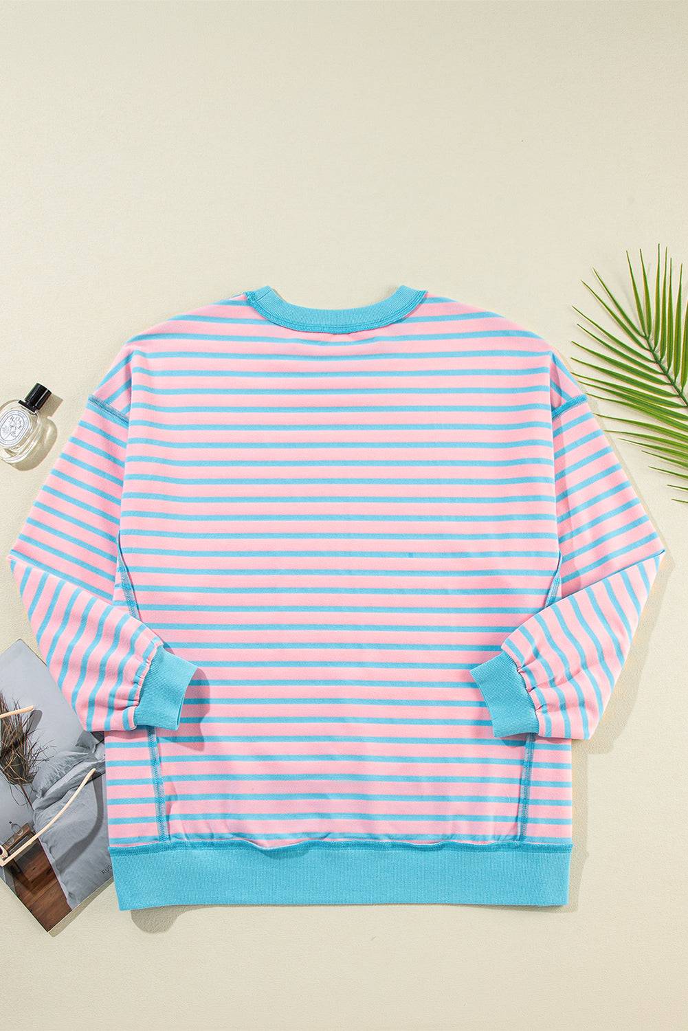 a pink and blue striped sweater next to a plant