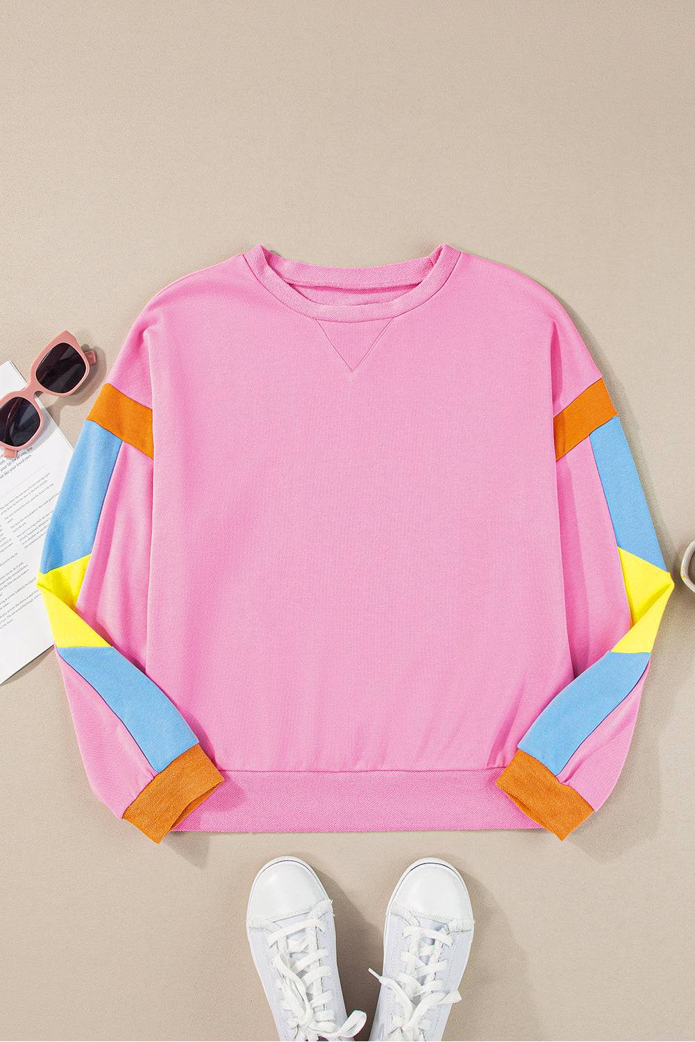 a pink sweater with colorful sleeves and a pair of white sneakers