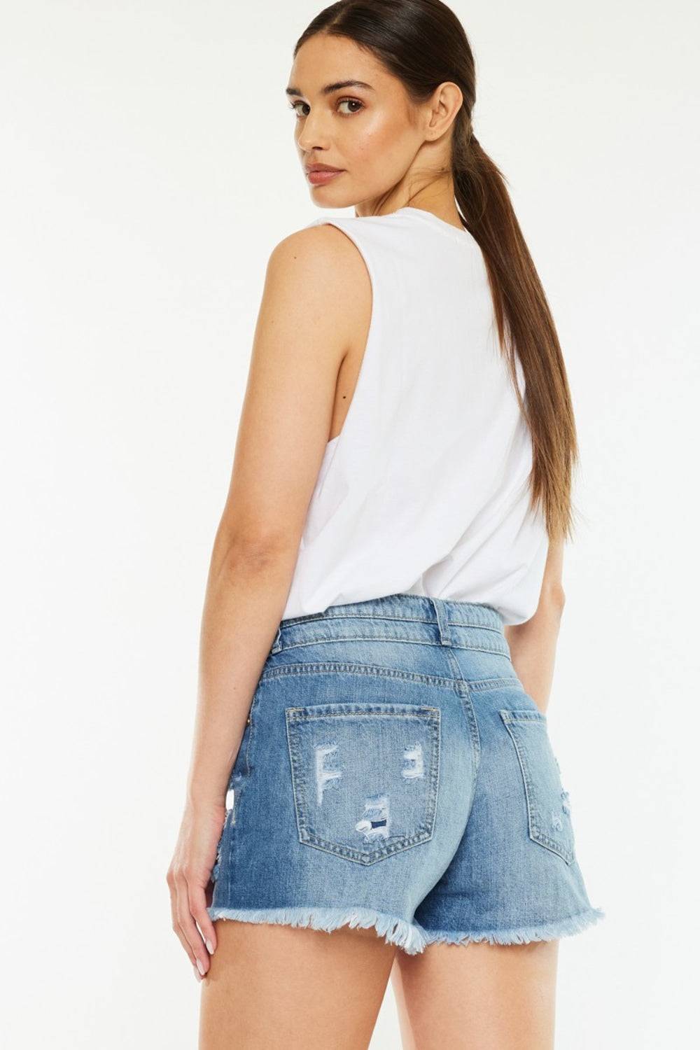 a woman in a white top and denim shorts