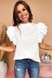 a woman wearing a white top with ruffled sleeves