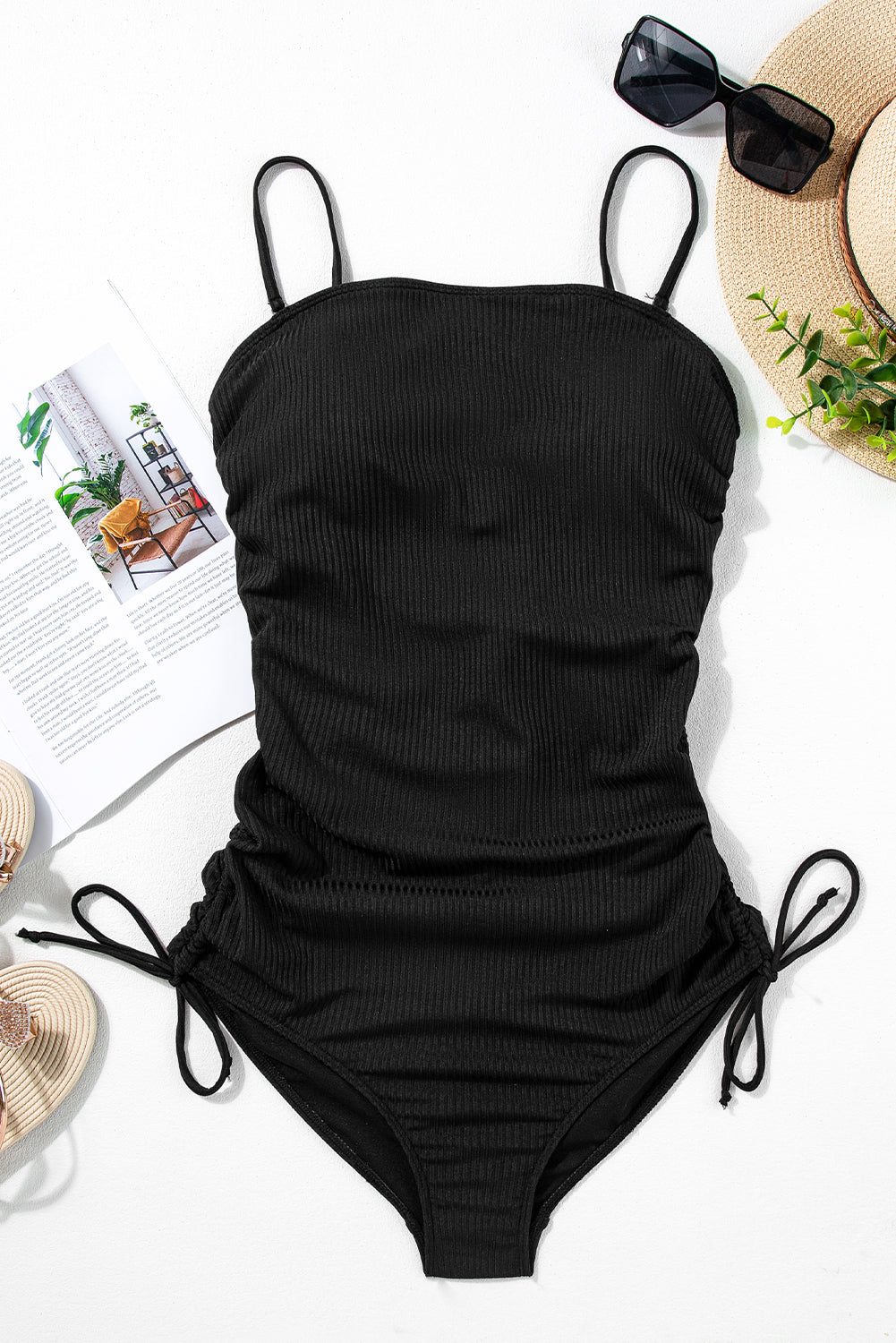 Flat lay of Black Ribbed Drawstring Sides Cutout One Piece Swimsuit with accessories, showcasing summer essentials from Faith & Co. Boutique.