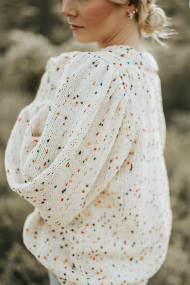 a woman wearing a white sweater with multicolored dots