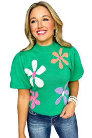 a woman wearing a green sweater with flowers on it