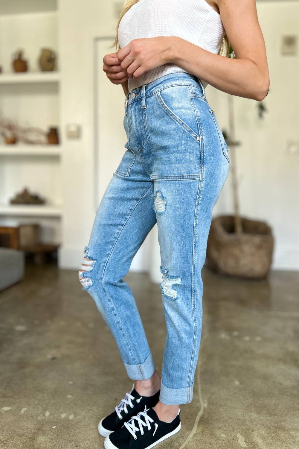 a woman in a white tank top and ripped jeans