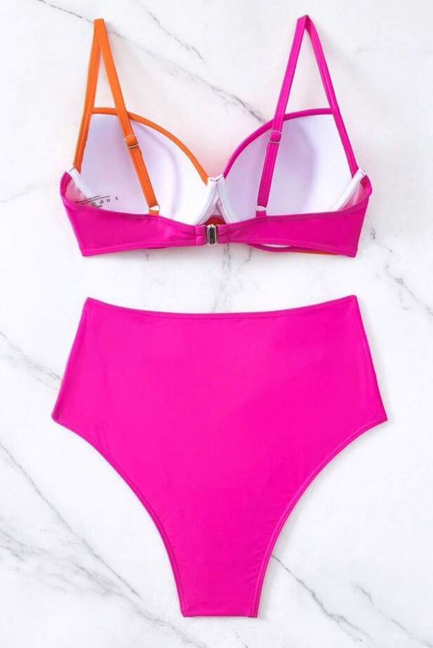 a pink bikinisuit with orange straps on a marble surface