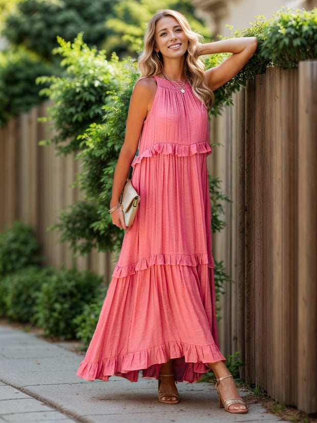 a woman in a pink dress leaning against a fence