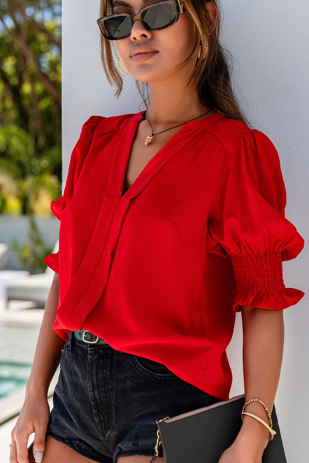 a woman wearing a red blouse and black sunglasses