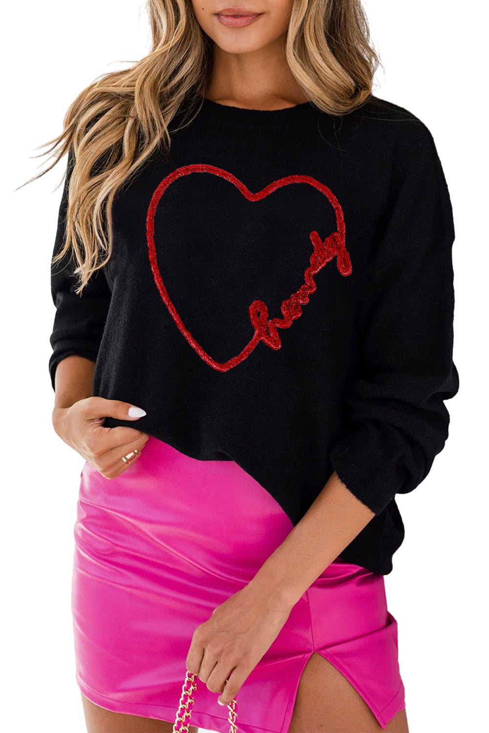 a woman wearing a black sweater with a heart on it