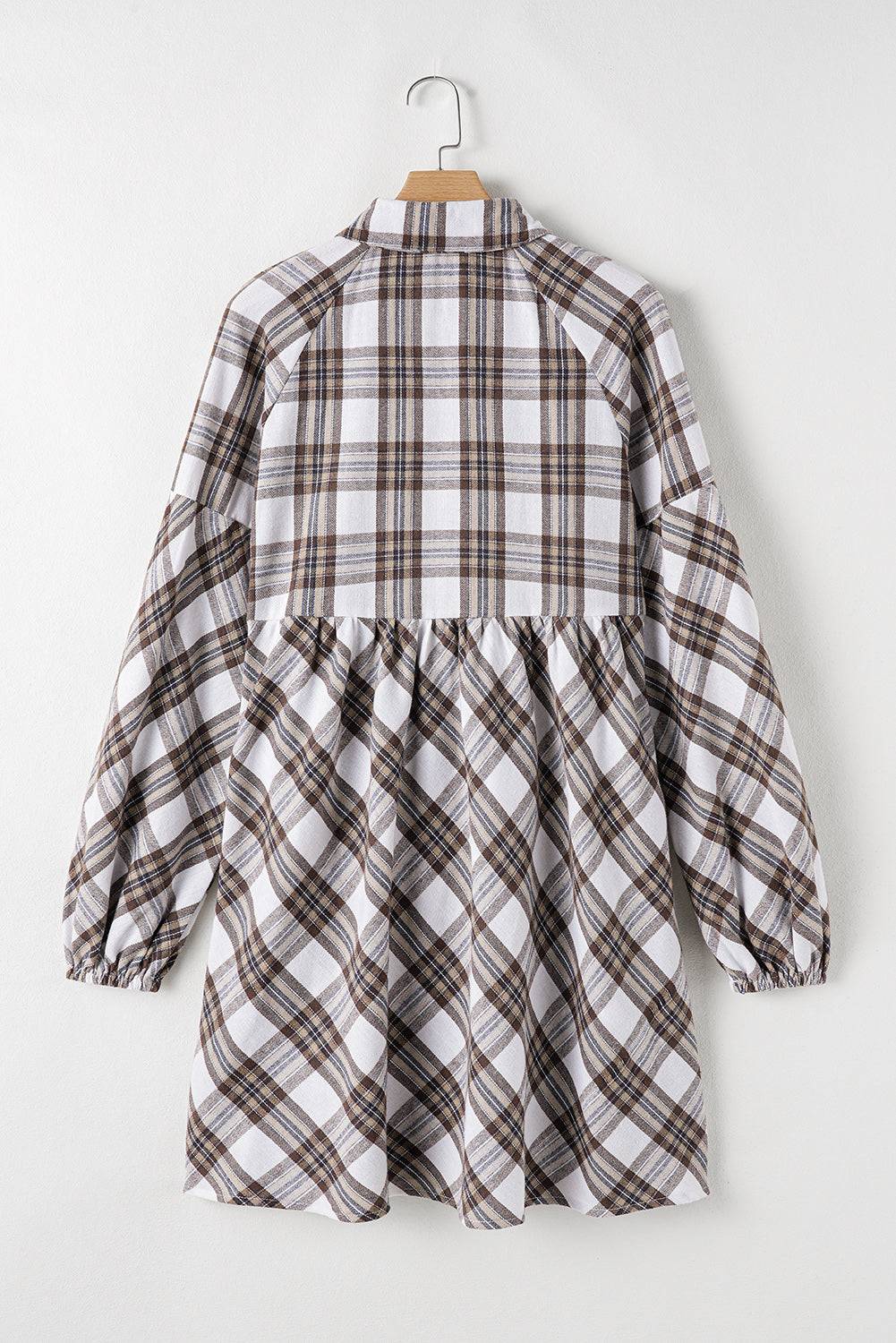 a white and brown checkered shirt hanging on a hanger