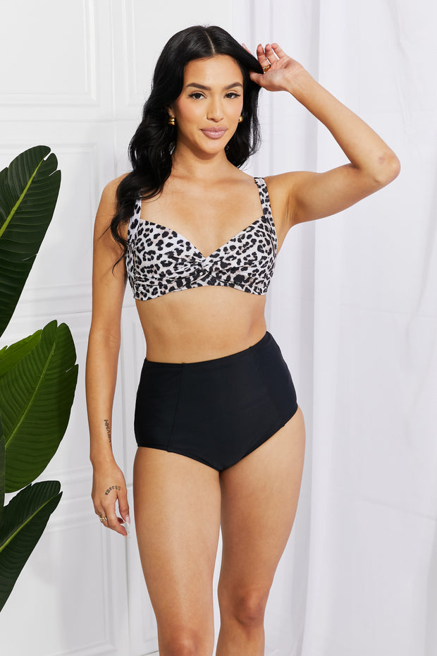 a woman in a leopard print bikini top and black high waist shorts