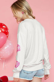 a woman wearing a white sweater with pink hearts on it