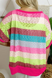 a woman standing in front of a wall wearing a pink and green striped top