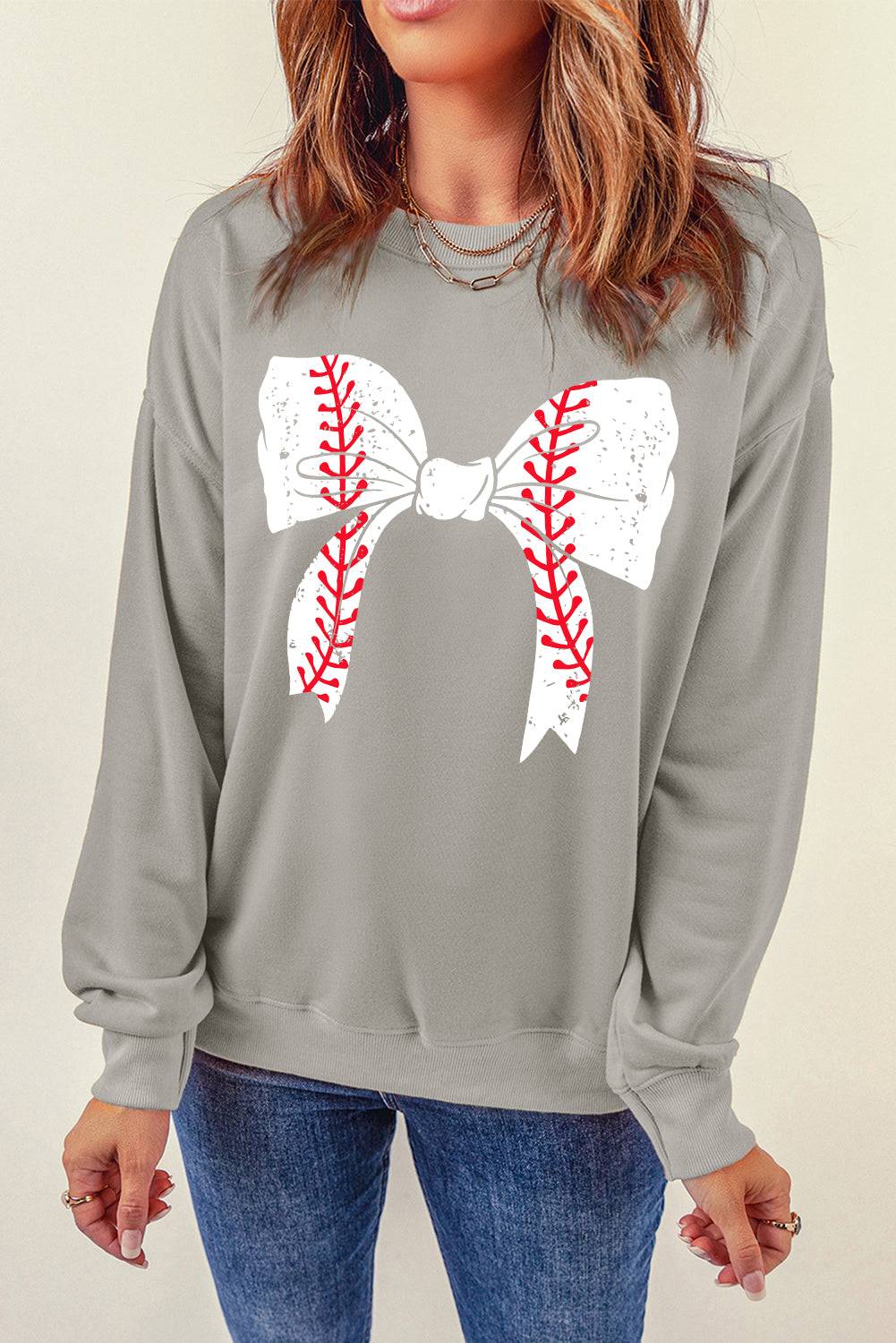 a woman wearing a baseball sweater with a bow