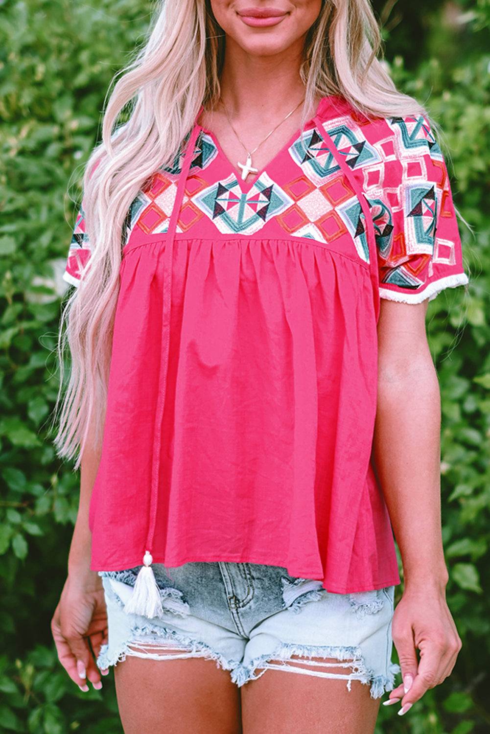 a woman wearing a red top and denim shorts