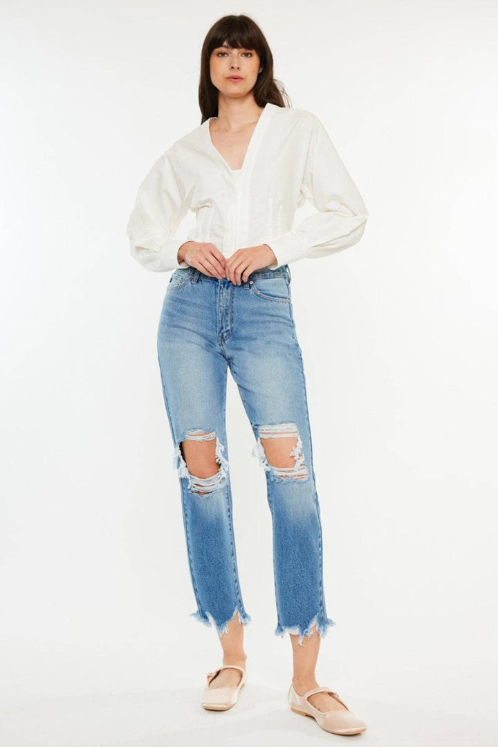 a woman wearing a white blouse and ripped jeans