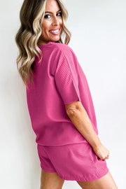 a woman in a pink top and shorts posing for a picture