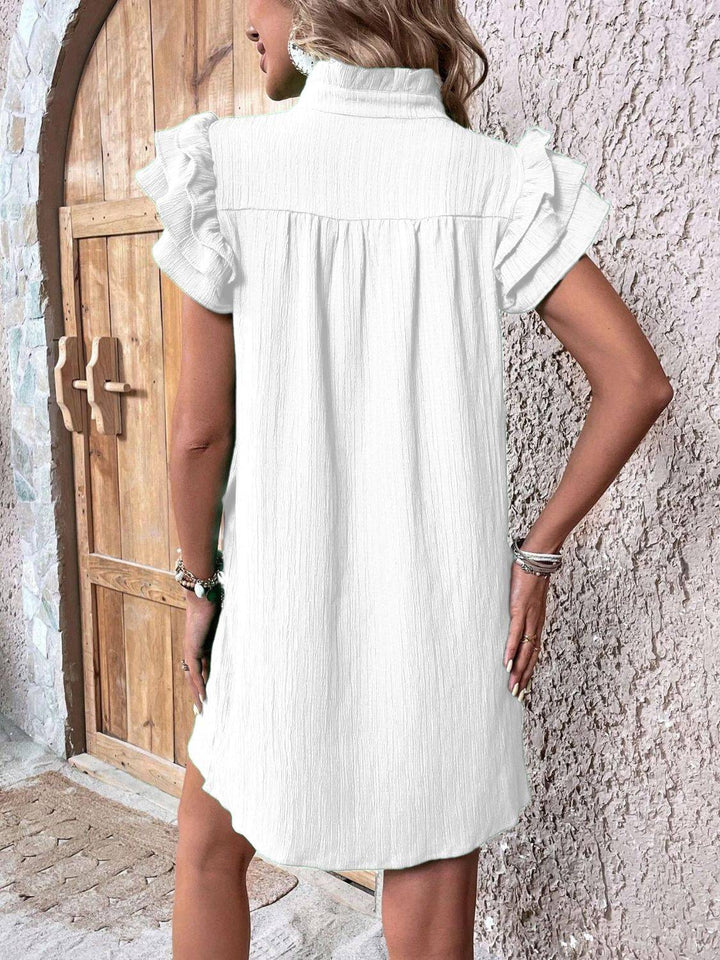 a woman standing in front of a door wearing a white dress