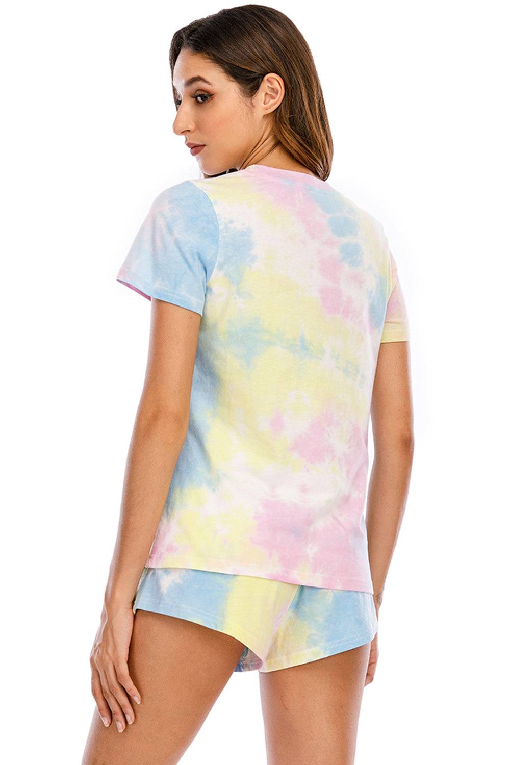 a woman wearing a tie dye shirt and shorts