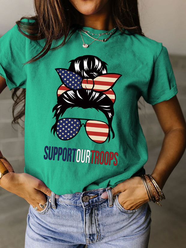 a woman wearing a green t - shirt that says support our troops