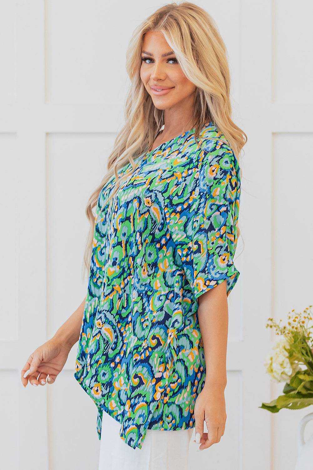 Side view of Green Abstract Print V Neck Half Sleeve Loose Fit Tunic Blouse paired with white pants, ideal for a bohemian summer style.