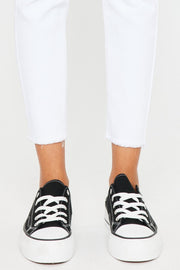 a close up of a person wearing white jeans and black sneakers