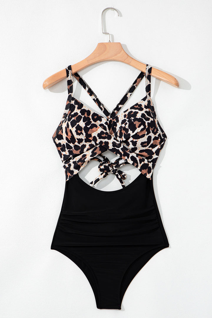 Flat lay of Black Leopard 2-tone Crossed Cutout Backless Monokini on hanger, showing front twist and cutout design, available at Faith & Co. Boutique.