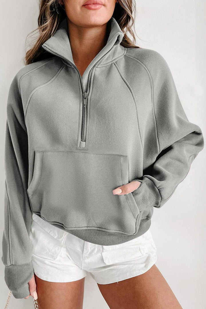 a woman wearing a gray sweatshirt and white shorts