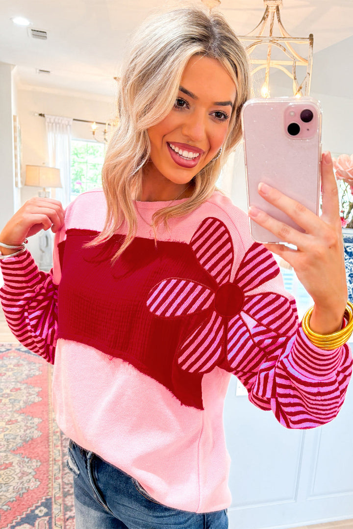 Pink Floral Patch Color Block Striped Sleeve Textured Top with bold red panel and striped flower applique, styled casually with jeans.