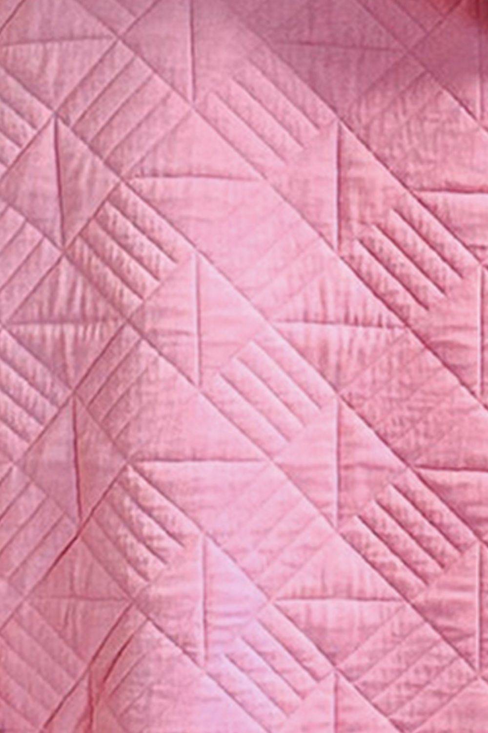 a close up of a pink quilt on a bed