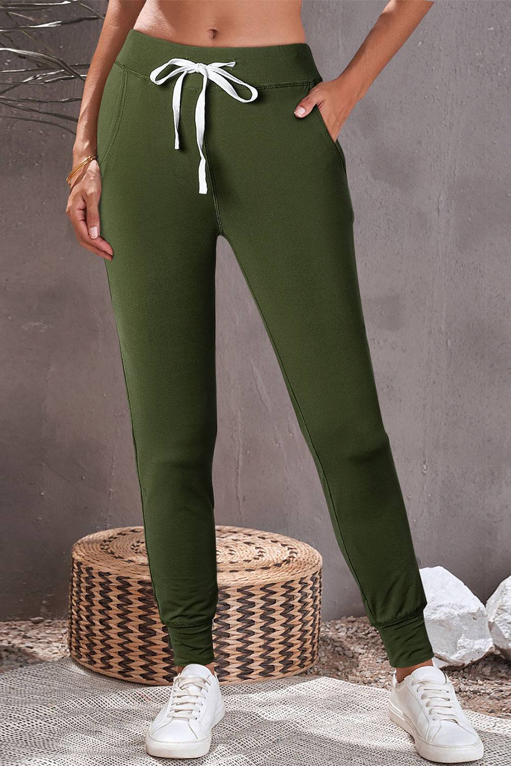 a woman wearing a crop top and green pants