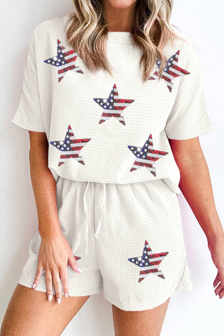 a woman wearing a white american flag top and shorts