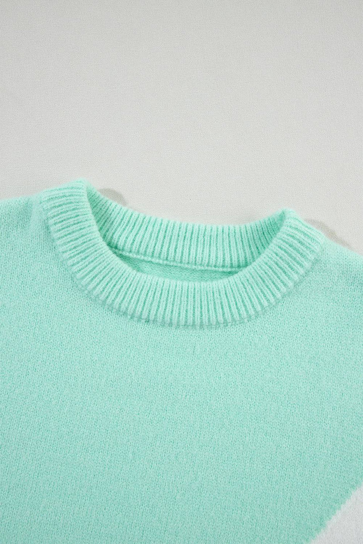 a green and white sweater is laying on a white surface